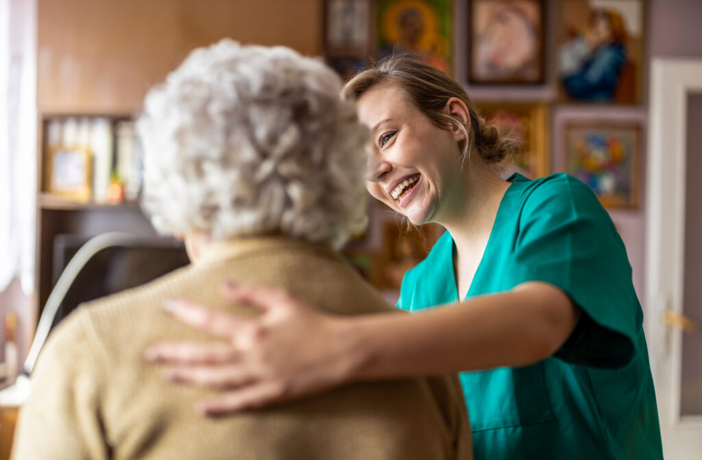 Caregiver smiling while assisting elderly person