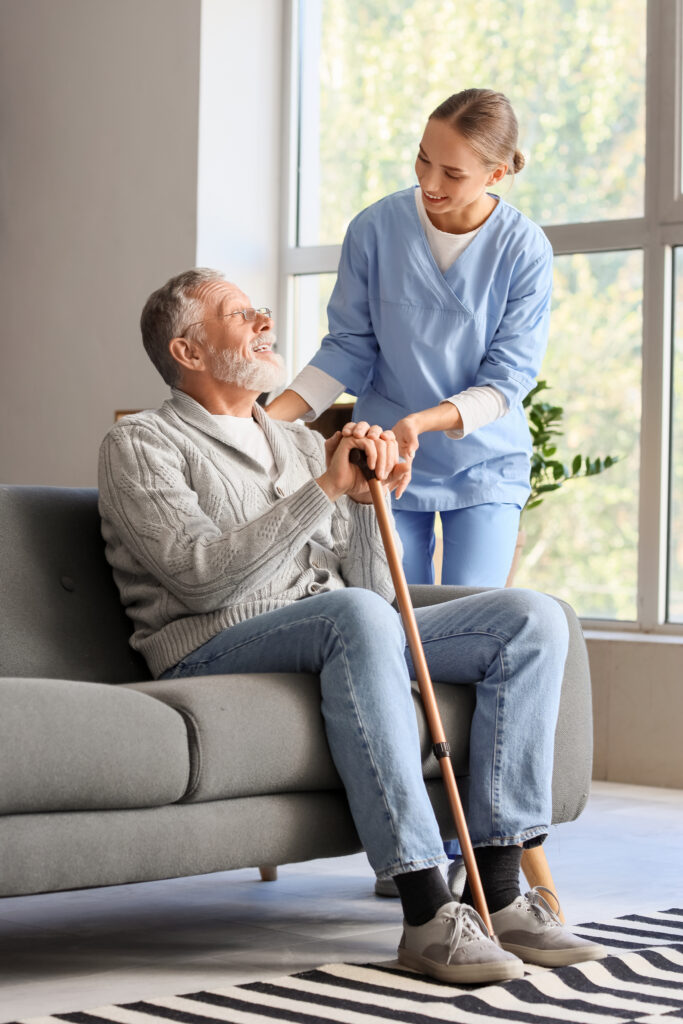 Caregiver assisting elderly man with cane